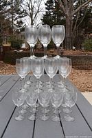 33 clear wine glasses displayed outdoors stacked in a pyramid on a gray table, showing uniform size and shape