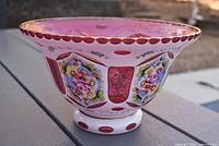 Side view of the Bohemian cranberry glass bowl showing the overall shape and floral hand-painted decoration with gold rim.
