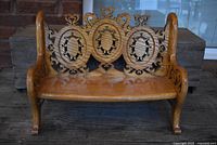 Front view of the carved wooden doll bench showing detailed circular medallion pattern on the backrest and curved armrests.