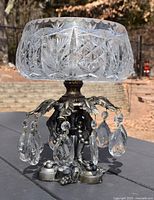Front view of the cut crystal compote bowl showing the detailed brilliant cut crystal pattern and the cast pot metal base with hanging crystal drops.