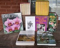 Photo showing the complete book sets, sealed Orchids book, and various individual books including Tales Mummies Tell, Real Rocks and Minerals, Sedimentology and Stratigraphy, and Roots Rocks and Recollections.