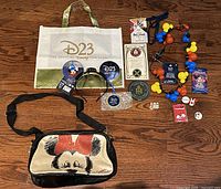 Top-down image showing entire collection spread on wooden floor including bags, pins, collectible figures, headbands, and fan event memorabilia.