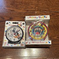 Two Looney Tunes alarm clocks in original packaging. Left is Bugs Bunny and Daffy Duck, right is Taz. Both new and wrapped in plastic.
