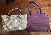 Silver woven purse and purple tote bag with handles on wooden surface
