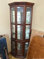 Front view of corner display cabinet showing upper glass inset doors, mirrored back, and lower glass inset door panels.