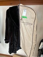 Coat hanging in included garment bag showing exterior.