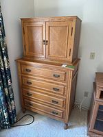 Front view of the high boy dresser showing the upper cabinet with double doors and four bottom drawers with metal handles.