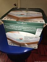 Box of Novaform ComfortLuxe gel infused memory foam mattress topper for double bed showing brand and product details.