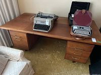 Full front view of the desk showing the top surface with two typewriters and the drawer arrangement.