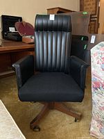 Front view of mid-century modern office chair with black vinyl and cloth seat, vertical stitched backrest, wood base and casters.