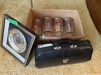 Overview of lot showing leather doctors bag, box of glass canisters and framed commemorative plate