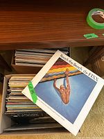 Box of LP records, showing 'Reach the Beach' by The Fixx in front and many other LPs stacked inside the box.