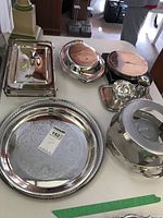 Image showing all silver plate items including large round tray, rectangular tray with handles, dome serving cover, coasters, small tray with glass holders, and warming pot.