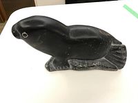 Front angled view of black soapstone seal carving showing facial details and body shape.