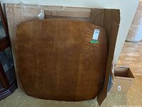 Square wooden table top with brown wood grain resting against cardboard box, showing label 119 and approximate size of 40 inches.