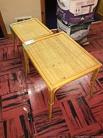 Two bamboo nesting tables stacked, showing natural bamboo frame and woven tops with stains on larger table.
