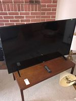 Front view of TV on wooden table with remote placed in front