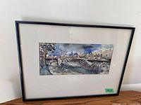 Full view of framed watercolour painting showing the landscape scene under glass with black frame and beige matting.