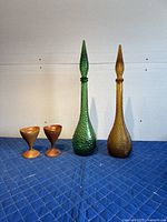 Full view of two hobnail glass decanters with stoppers and two teak candle holders on protective cloth