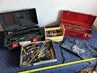 Wide view of lot showing large black Jobmate toolbox open with tools inside, wooden toolbox, metal red toolbox, and loose tools in a cardboard box.