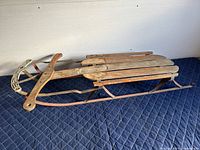 Full view of the old wooden sled showing overall structure with worn wooden slats and metal runners.