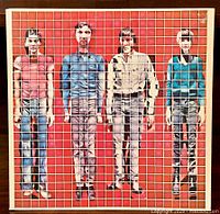 Front of the vinyl LP album cover showing the band members behind a white grid on a red background.
