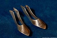 Angle view of both earrings against dark fabric background showing shape and finish