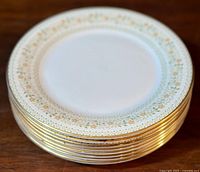 Stack of eight side plates with floral paisley border pattern and gold trim, showing the overall set and edge detail.