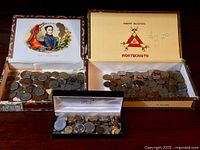 Three boxes of assorted world coins, including a Bolivar-themed box, Montecristo cigar box, and a Montblanc pen case filled with coins.