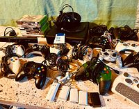 Wide view of Xbox gaming lot including 2 consoles, multiple controllers, Kinect sensor, battery packs, and games.