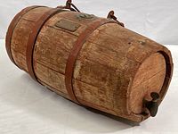 Side view of the small vintage wood cask showing the iron rims, brass plaque, and spigot tap.