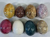 Overview of eight polished stone eggs showing variety of colors and polished surfaces.