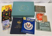 Collection of six vintage stamp albums and one booklet displayed on table with small bag of loose stamps