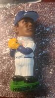 Front side of the Fergie Jenkins bobblehead showing detailed facial features, Cubs pinstriped uniform, blue cap, yellow glove, and green base with name inscription.