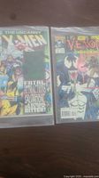 Photo showing two Marvel comic books side by side in plastic covers: The Uncanny X-Men and Venom: Funeral Pyre