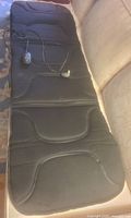 Full length view of black massage pad laid flat showing wired remote