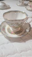 Photo of Royal Albert Chelsea Bird bone china cup and matching saucer with floral and bird motif with gold trim under natural lighting.