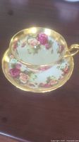 Teacup placed inside matching saucer showing floral design and gold trim on rim and handle