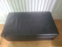 Top angled view of brown storage bench showing stitched grid pattern on leatherette surface