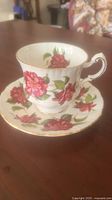 Bone china teacup with floral camellia pattern and gold trim on a wooden table