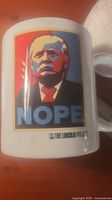 Close-up of the white ceramic mug showing the stylized image of Donald Trump in poster style with the text 'NOPE' and The Lincoln Project logo below.