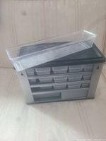 Front view of the metal storage utility box with a clear plastic tray removed and resting on top to display its size and design.