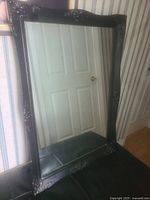 Full view of the rectangular vintage mirror showing the entire black frame and reflective surface.