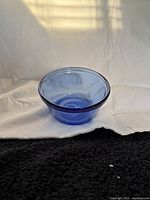 Photo of a single small translucent blue glass bowl with smooth round edges, part of the custard cups set.