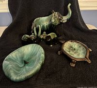 Blue Mountain Pottery ashtray, elephant figurines, turtle candy dish with lid, and mug arranged on black background