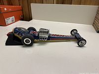 Side view of blue Cox Eliminator 2 dragster tether car on black launching stand