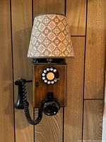 Front view of vintage wall telephone converted to lamp with decorative fabric lampshade.