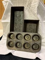 Photo showing two Ovenex loaf pans and one 8-cup muffin pan with textured starburst pattern inside.