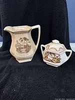 Pitcher and sugar dish shown against black background highlighting their shape and design.