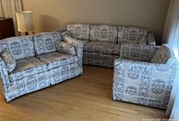 Wide view of the sofa, love-seat, and chair arranged together, showing upholstery pattern and shape.